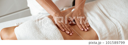 Female client receiving stomach massage in spa salon Female client receiving stomach massage in spa salon 101589799