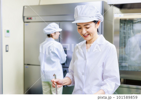 厨房で料理を作る白衣を着た女性調理師 101589859