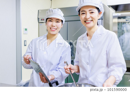 厨房で料理を作る白衣を着た女性調理師 101590000