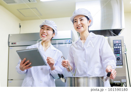 厨房で料理を作る白衣を着た女性調理師 101590180