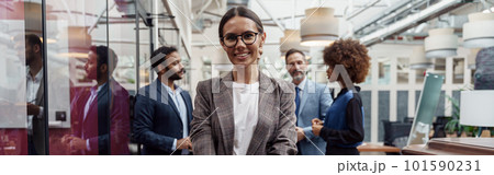 Portrait of smiling businesswoman in glasses standing in modern office on colleagues background 101590231