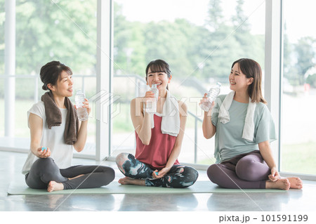 スポーツジムのヨガ教室で休憩をしながら水分補給・スポーツドリンクを飲む女性達 スポーツジムのヨガ教室で休憩をしながら水分補給・スポーツドリンクを飲む女性達 101591199