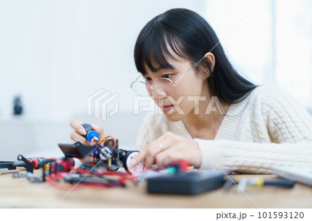 Happy cheerful Asian ethnicity female university student learning about robotic and programing by herself, woman assemble a robot and coding. 101593120
