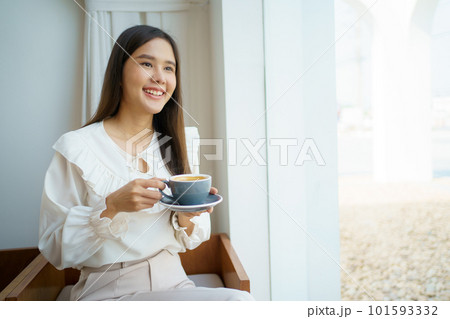 Asian businesswoman holding a coffee cup on hand during relaxing in the coffee shop. Asian smart and good looking businesswoman taking a break in coffee shop. 101593332