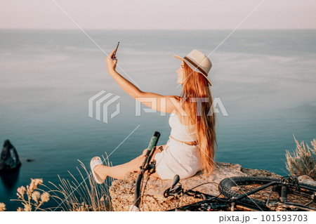 Woman travel sea. Happy tourist in hat enjoy taking picture outdoors for memories. Woman traveler posing on the beach at sea surrounded by volcanic mountains, sharing travel adventure journey Woman travel sea. Happy tourist in hat enjoy taking picture outdoors for memories. Woman traveler posing on the beach at sea surrounded by volcanic mountains, sharing travel adventure journey 101593703