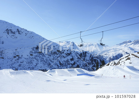 Ski lifts over snow covered landscape with mountains in background on sunny day, winter holiday travel concept 101597028