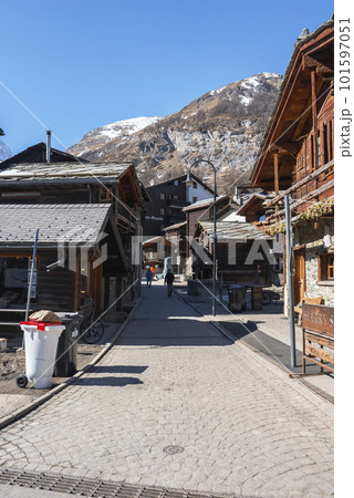 Diminishing perspective of street between luxury wooden chalet buildings in old town with mountain and clear blue sky in background during sunny day at Zermatt, Switzerland, Winter travel concept Diminishing perspective of street between luxury wooden chalet buildings in old town with mountain and clear blue sky in background during sunny day at Zermatt, Switzerland, Winter travel concept 101597051