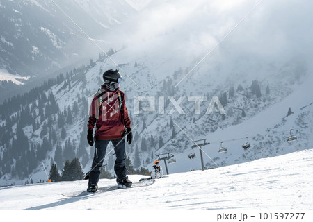 Tourist with snowboard on snow covered mountain with beautiful landscape in background during winter vacation, winter holiday travel concept Tourist with snowboard on snow covered mountain with beautiful landscape in background during winter vacation, winter holiday travel concept 101597277