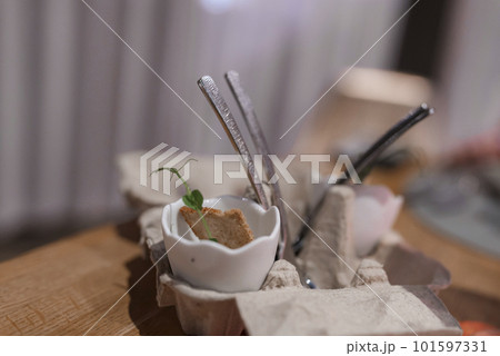 Closeup of food with herb garnished in eggshell in egg carton on wooden table at fancy restaurant in luxury hotel Closeup of food with herb garnished in eggshell in egg carton on wooden table at fancy restaurant in luxury hotel 101597331