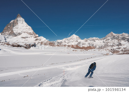 Young man skiing in Zermatt ski resort right next to the famous Matterhorn peak. Beautiful sunny day for snowboarding. Winter sports concept. 101598134