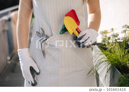 Middle selection of female in overall with garden tools stand on balcony and preparing for landing 101601428