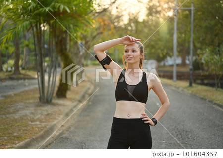 Portrait of athletic woman taking a break from fitness training in the park with beautiful sunlight Portrait of athletic woman taking a break from fitness training in the park with beautiful sunlight 101604357