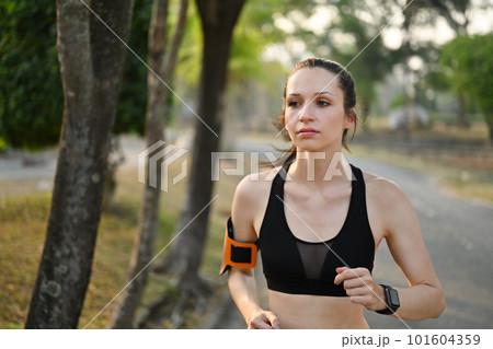 Delighted athletic woman in sportswear jogging in public park. Healthy lifestyle, sport, wellness concept Delighted athletic woman in sportswear jogging in public park. Healthy lifestyle, sport, wellness concept 101604359