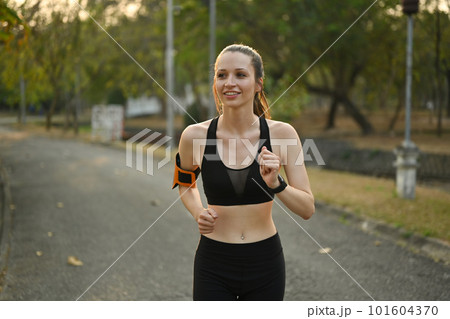 Delighted athletic woman in sportswear jogging in public park. Healthy lifestyle, sport, wellness concept 101604370