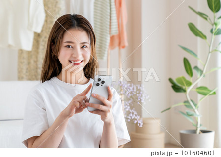 リビングでスマホを見る若い女性 リビングでスマホを見る若い女性 101604601