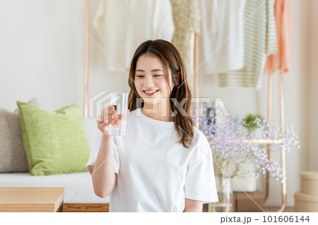 リビングでミネラルウォーターを飲む若い女性 リビングでミネラルウォーターを飲む若い女性 101606144