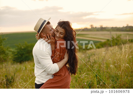 Couple in a field. Woman in a brown dress. Sunset background. 101606978