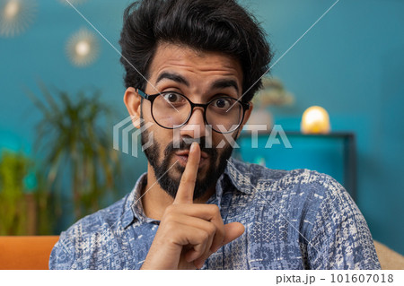 Indian man presses finger to lips makes silence hush sign do not tells gossip secret, quiet at home 101607018
