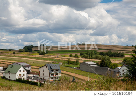 Countryside village. Rural scenery. Nature landscape. White cottage houses on meadow hills with yellow green field and fluffy sky clouds daylight panorama. Countryside village. Rural scenery. Nature landscape. White cottage houses on meadow hills with yellow green field and fluffy sky clouds daylight panorama. 101610194