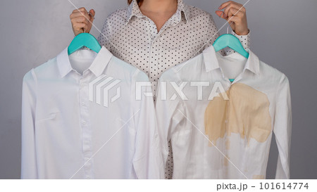 A woman compares two white shirts before and after washing. The girl is holding one blouse, clean and ironed, and the other, dirty with coffee stains A woman compares two white shirts before and after washing. The girl is holding one blouse, clean and ironed, and the other, dirty with coffee stains 101614774