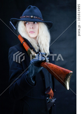 Old west blonde girl in black hat with gun 101614995
