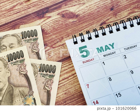 木目調の机に置かれた5月カレンダーと3万円 101620066