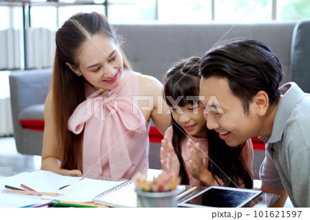 Happy Asian family, father, mother, and daughter living together in the living room. Parent spending a time with their lovely daughter in the free time in weekend together. Happy Asian family, father, mother, and daughter living together in the living room. Parent spending a time with their lovely daughter in the free time in weekend together. 101621597