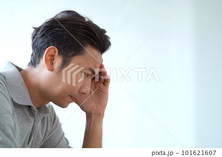 Unhappy Asian young man sitting on the sofa in living room and holding his hands together, stressful Asian man sitting alone in living room. A man worried and concerned about something. Unhappy Asian young man sitting on the sofa in living room and holding his hands together, stressful Asian man sitting alone in living room. A man worried and concerned about something. 101621607