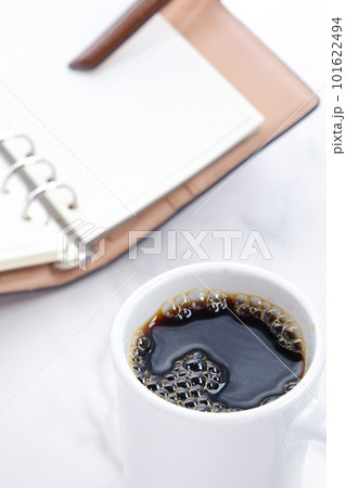 コーヒーを飲みながらシステム手帳を開いて仕事の段取りを考える 101622494