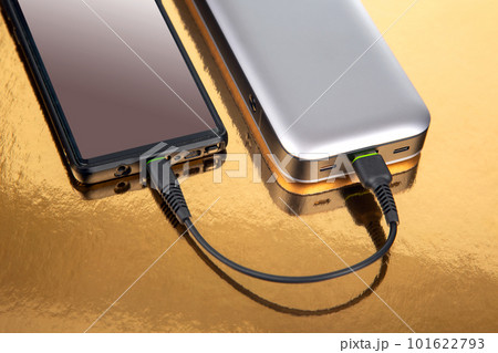Powerbank charges a smartphone on a golden background. Powerbank charges a smartphone on a golden background. 101622793