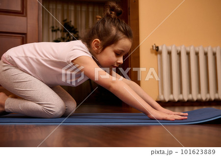 Close-up little girl stretching her body in Balasana pose, sitting