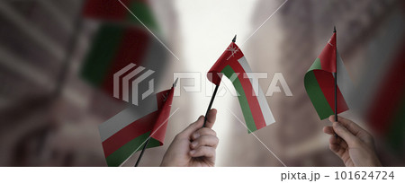 A group of people holding small flags of the Oman in their hands A group of people holding small flags of the Oman in their hands 101624724