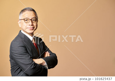 腕組みをしながら視線を向けるスーツ姿のシニア男性　ビジネスイメージ 101625437
