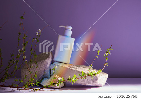 Blank plastic cosmetics container for cream or shampoo. Cosmetics bottle mockup with stone, flower and rainbow on purple background 101625769
