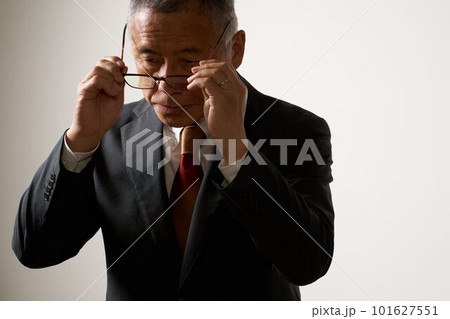 うつむき加減で眼鏡を外すスーツ姿のシニア男性 うつむき加減で眼鏡を外すスーツ姿のシニア男性 101627551
