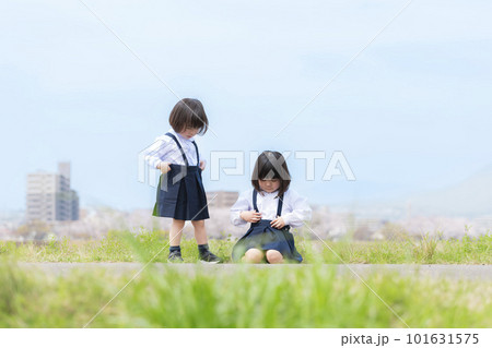 春の河川敷で遊ぶ幼稚園の制服を着た姉妹 春の河川敷で遊ぶ幼稚園の制服を着た姉妹 101631575