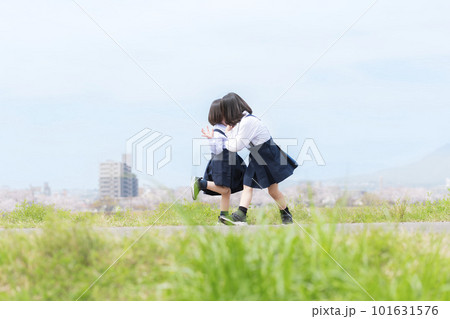 春の河川敷で遊ぶ幼稚園の制服を着た姉妹 101631576