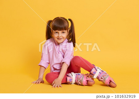 Cute little girl with happy facial expression looks smiling at camera, going to roller skate, active lifestyle for kids, summer leisure time, female kid with two ponytails. 101632919