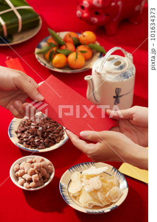 A table decorated in red for the Lunar New Year celebration with food and drink. People giving lucky money to each other A table decorated in red for the Lunar New Year celebration with food and drink. People giving lucky money to each other 101634373