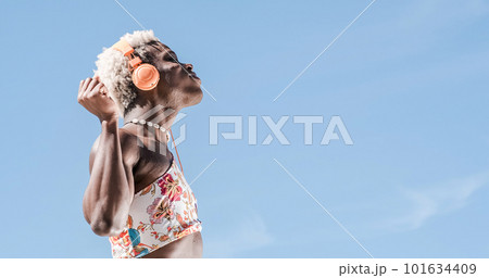 Transgender person dancing while listening to music with headphones outdoors. 101634409