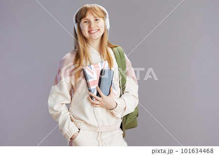 Portrait of happy trendy pupil in beige tracksuit using phone Portrait of happy trendy pupil in beige tracksuit using phone 101634468