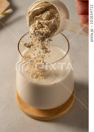 Pouring protein powder from scoop, in glass with milkshake. Pouring protein powder from scoop, in glass with milkshake. 101634712