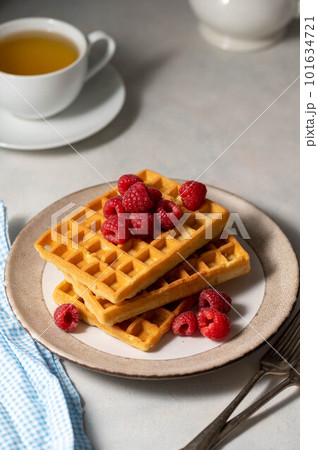 Breakfast waffles with berries in plate served with cup of tea. 101634721