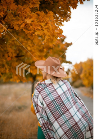 autumn woman in a green dress, brown hat, plaid, against the background of an autumn tree autumn woman in a green dress, brown hat, plaid, against the background of an autumn tree 101635204