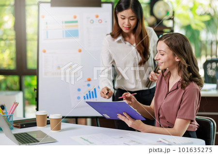Concept of business office woman working,Businesswoman smile while working about her invesment plan with analyzing document and business investment graph data by using laptop on desk in workstation. Concept of business office woman working,Businesswoman smile while working about her invesment plan with analyzing document and business investment graph data by using laptop on desk in workstation. 101635275