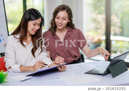 Concept of business office woman working,Businesswoman smile while working about her invesment plan with analyzing document and business investment graph data by using laptop on desk in workstation. 101635283