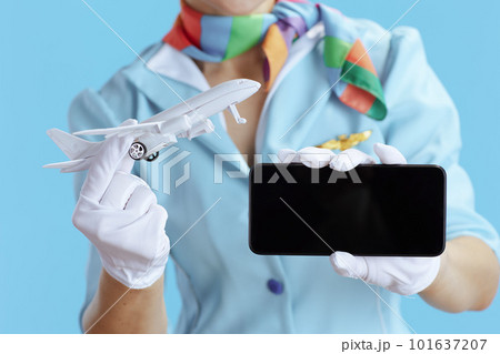 Female air hostess on blue showing smartphone blank screen Female air hostess on blue showing smartphone blank screen 101637207