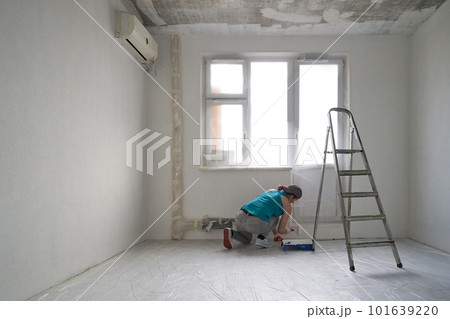 Woman paints the wall with a roller 101639220