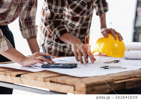 Architect and Engineer working with blueprints for architectural plan, engineer sketching a construction project, green energy concept 101641039