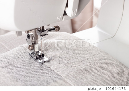 Modern sewing machine presser foot with linen fabric and thread, closeup Modern sewing machine presser foot with linen fabric and thread, closeup 101644178
